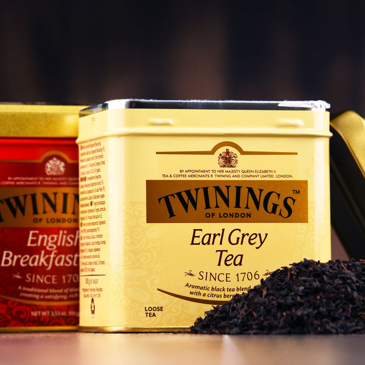 Twinings-Banner: glazen theekop, waarin thee wordt geschonken vanuit een glazen theepot. De achtergrond is groen en zonnig.